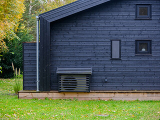 Modern wooden house exterior featuring a heat pump system installed outside. Heat pump camouflaged...