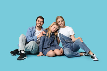 Happy family in stylish denim clothes sitting on blue background