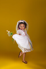 Cheerful child dressed as a bride holding a bouquet of flowers and posing for the camera.