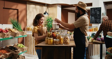 Client talking with seller in pesticides free food shop, inquiring about products ethical sourcing. Woman in local store with sustainable supply chain chatting with trader about pantry staples