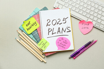 Sticky notes with to do plans, notebook and computer keyboard on grey background. New year goals concept