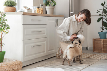 Pretty young woman with cute pug dog at home