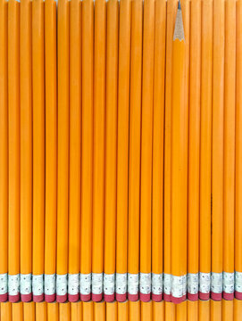 Orange pencils vertical background with one sharpened pencil for back to school and education concept.