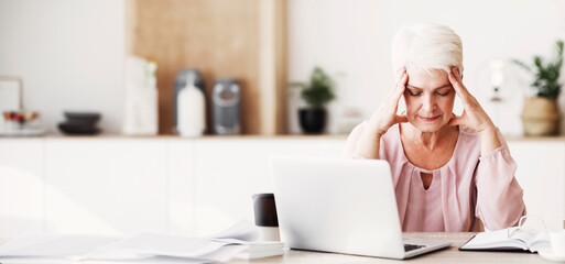 Feeling Tired And Stressed. Senior business woman working on laptop, keeping eyes closed, touching...