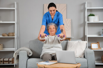 Obraz premium Senior woman training with dumbbells and physical therapist at home