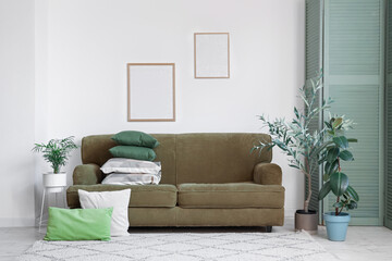 Interior of living room with stack of pillows on green sofa