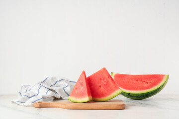 Wooden board with pieces of sweet watermelon on white background