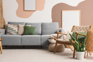 Armchair with cushions and cozy sofa in interior of living room