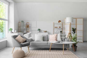 Interior of living room with grey sofa, armchair and soft cushions