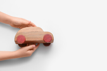 Child's hands with wooden toy car on white background