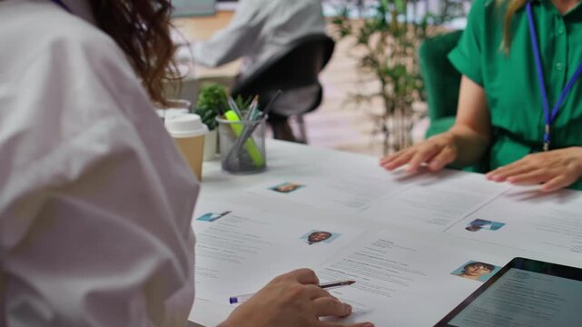 HR staff going through the selection process phase of the recruitment activity, choosing the best applicant based on their qualifications in the resume. Recruiters seeking talent. Camera B.