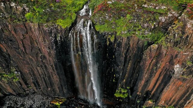 Aerial dramatic view of Mealt Falls and Kilt rock in the Scottish Highlands of Portree, Scotland. Viewpoint at the Isle of Skye in United Kingdom with a waterfall falling down a rough cliff in ocean.