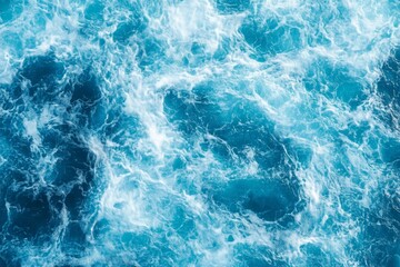 Fototapeta premium Top view of blue ocean water with intricate wave textures and water splashes, creating an abstract background of the sea surface, showcasing the dynamic movement and vibrant blue tones of the ocean.