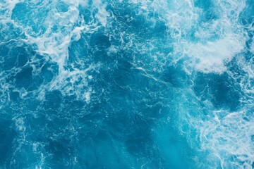 Fototapeta premium Top view of blue ocean water with intricate wave textures and water splashes, creating an abstract background of the sea surface, showcasing the dynamic movement and vibrant blue tones of the ocean.