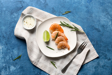 Plate with tasty boiled shrimps, lime and rosemary on blue background