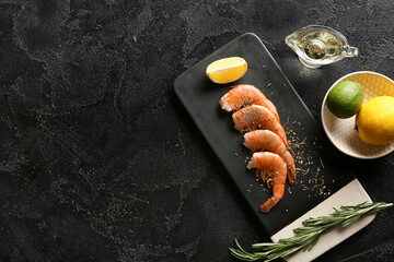 Board with tasty boiled shrimps, rosemary and lemon on black background