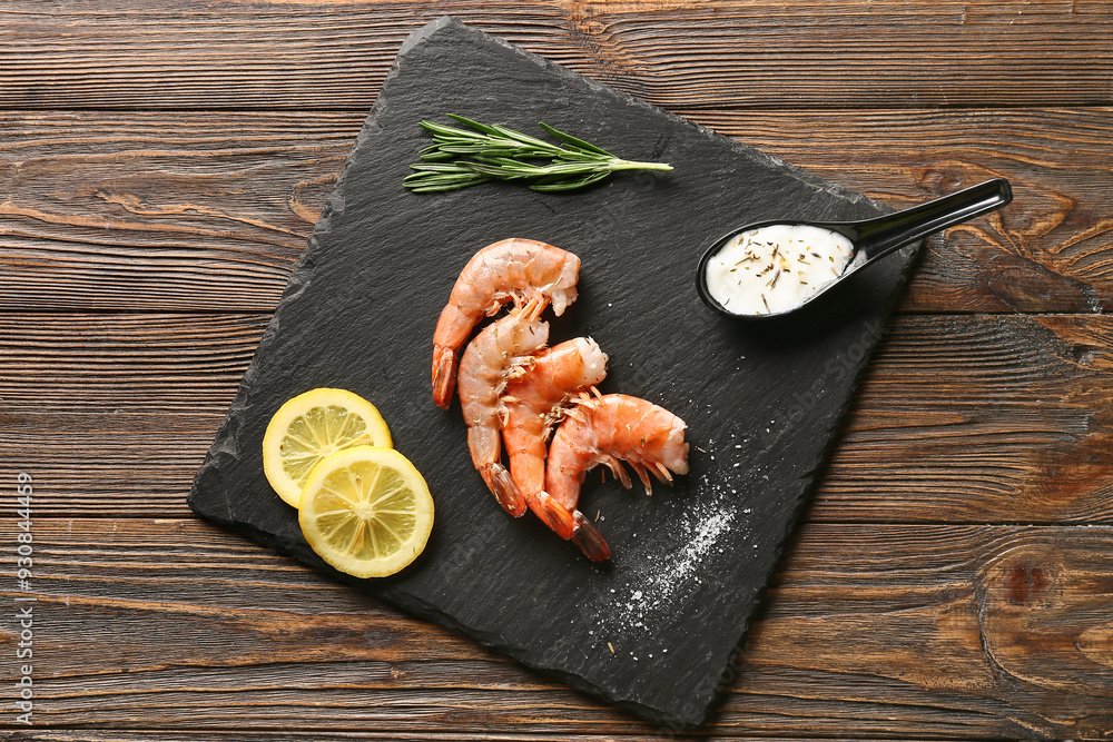 Sticker black board with tasty boiled shrimps, lemon and sauce on wooden background