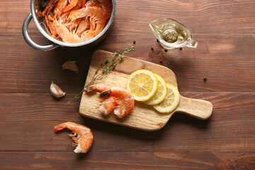 Board and pot with tasty boiled shrimps on wooden background