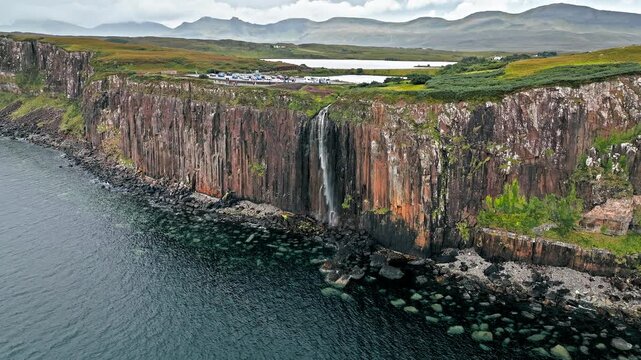 Aerial dramatic view of Mealt Falls and Kilt rock in the Scottish Highlands of Portree, Scotland. Viewpoint at the Isle of Skye in United Kingdom with a waterfall falling down a rough cliff in ocean.