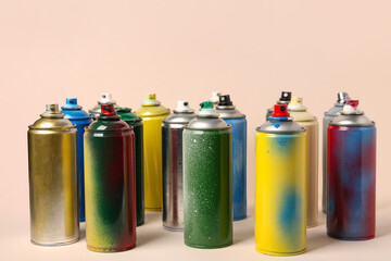 Many spray paint cans on beige background