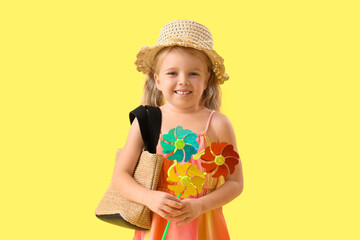 Cute little girl with toy windmill on yellow background