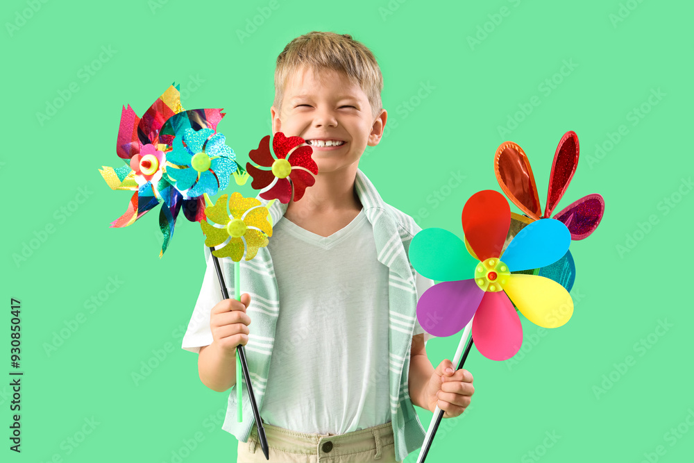 Wall mural cute little boy with toy windmills on green background