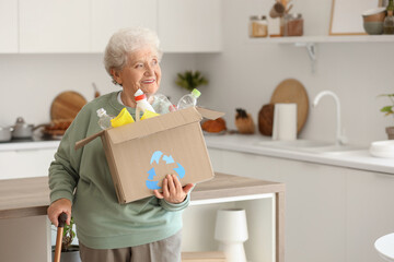 Senior woman with box of garbage in kitchen. Waste sorting concept