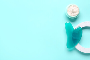 Jar of cosmetic product, plaster stand and facial massage tool on turquoise background