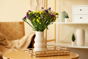 Chairs and coffee table with wild flowers in vase in room. Closeup