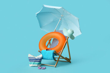 Deck chair, beach umbrella, bag, hat, towel, flip-flops and inflatable ring on blue background