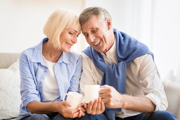 Obraz premium Tender mature couple drinking tea at autumn day, spending weekend at home