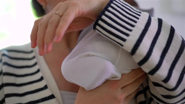 Mother gently lifts newborn close, checking the baby's diaper by smelling it to see if he pooped. a relatable and tender moment in everyday parenting, full of care and attention