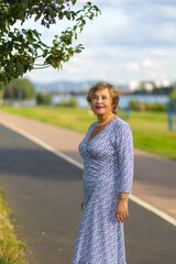 Fototapeta premium Woman in blue floral dress enjoying a sunny day by the riverbank