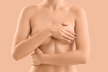 Naked woman on beige background, closeup. Breast cancer awareness concept