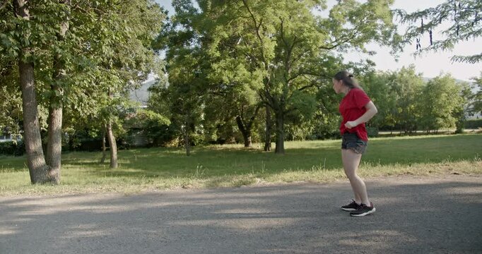 Young girl performing a modern dance routine in a sunlit park. Energy, freedom, and outdoor expression in a natural setting.