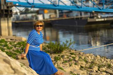 A woman enjoying the riverside view while sitting on rocks beneath