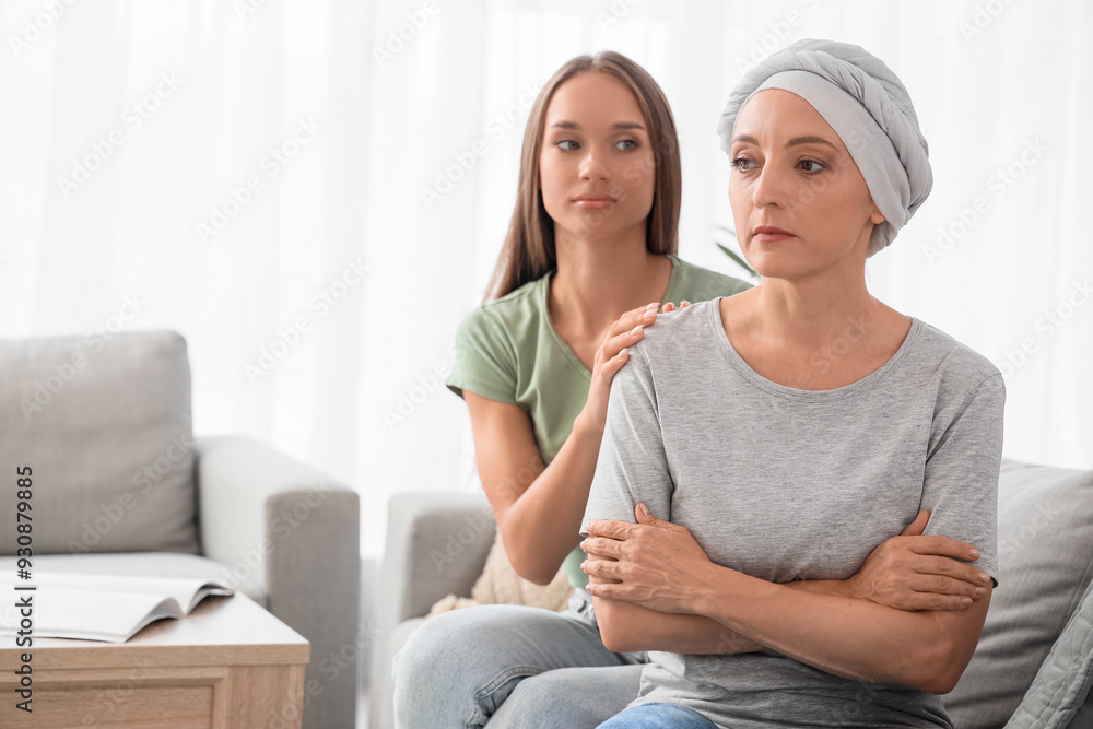 Poster Sad mature woman after chemotherapy with her daughter sitting on sofa at home