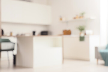 Blurred view of light kitchen with white counters and dining table