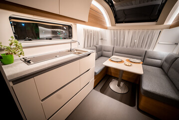 Interior with,tables,refrigerator,kitchen corners,ceiling ligthning,couches,living space in modern Slovenian camper van Adria.