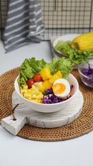 A bowl of salad with corn, egg, mango, tomato, lettuce, red cabbage