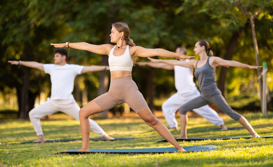 Motivated young girl performing standing lunging asana Virabhadrasana, or Warrior pose during...