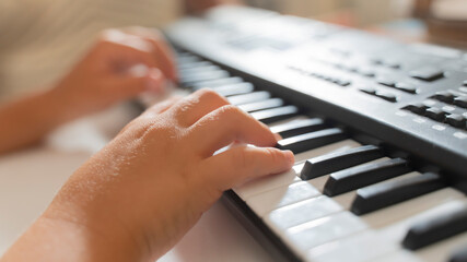Fototapeta premium close-up of a child's hands playing the keys of a piano synthesizer