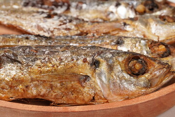 Fried Gereh Keranjang (pindang keranjang) fish, a traditional Indonesian side dish, served on a wooden plate and photographed with a white background.