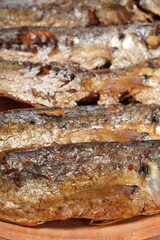 Fried Gereh Keranjang (pindang keranjang) fish, a traditional Indonesian side dish, served on a wooden plate and photographed with a white background.