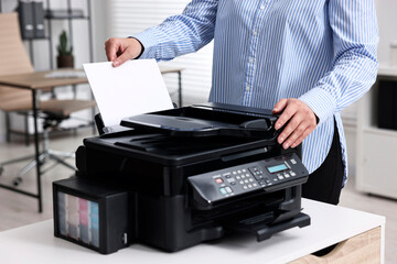 Woman using modern printer at workplace indoors, closeup