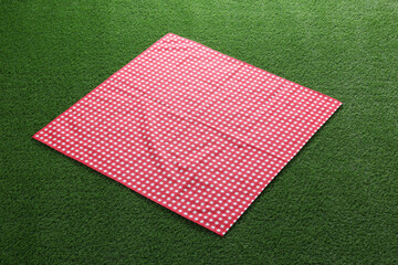 Red checkered picnic tablecloth on green grass