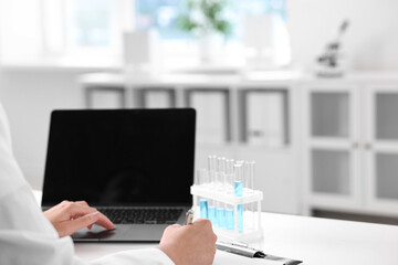 Doctor with laptop at table in clinic, closeup view
