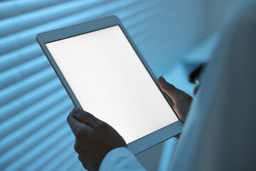 Doctor using tablet in hospital at night, closeup