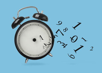 Numbers flying away from alarm clock on light blue background. Time related concepts