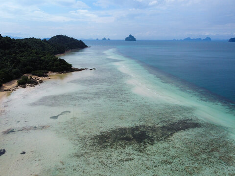 Aerial view of remote tropical beach at low tide with sanbar and coral reef on a sunny day, with other islands in the background, Koh Kradan, Trang, Thailand